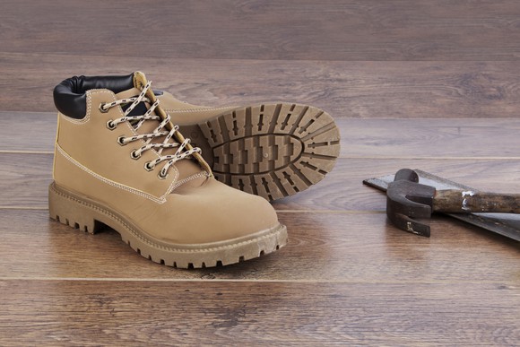 Leather boots on the floor next to a hammer