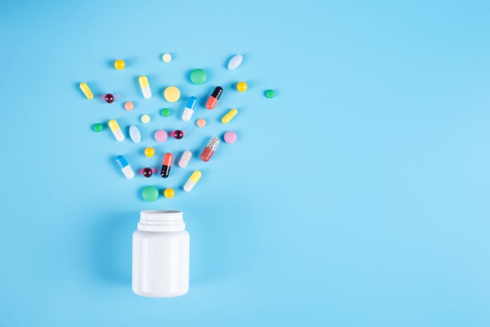 Assorted pharmaceutical medicine pills, tablets and white bottle on blue background