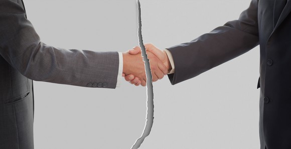 Ripped picture of two men in suits shaking hands