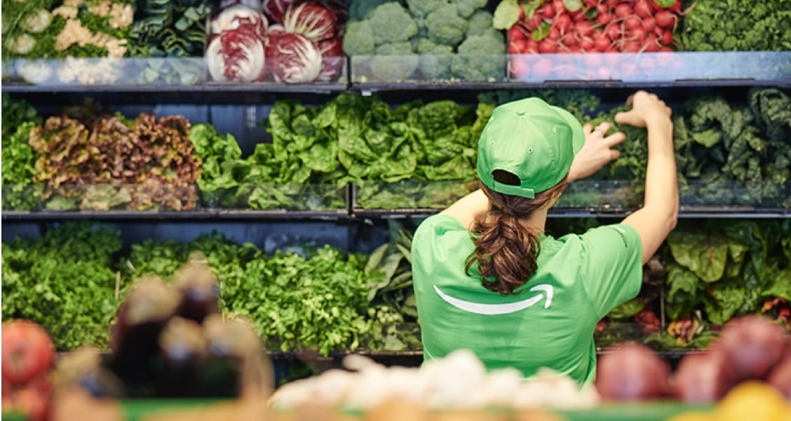A worker at the Amazon Go Grocery store stock produce