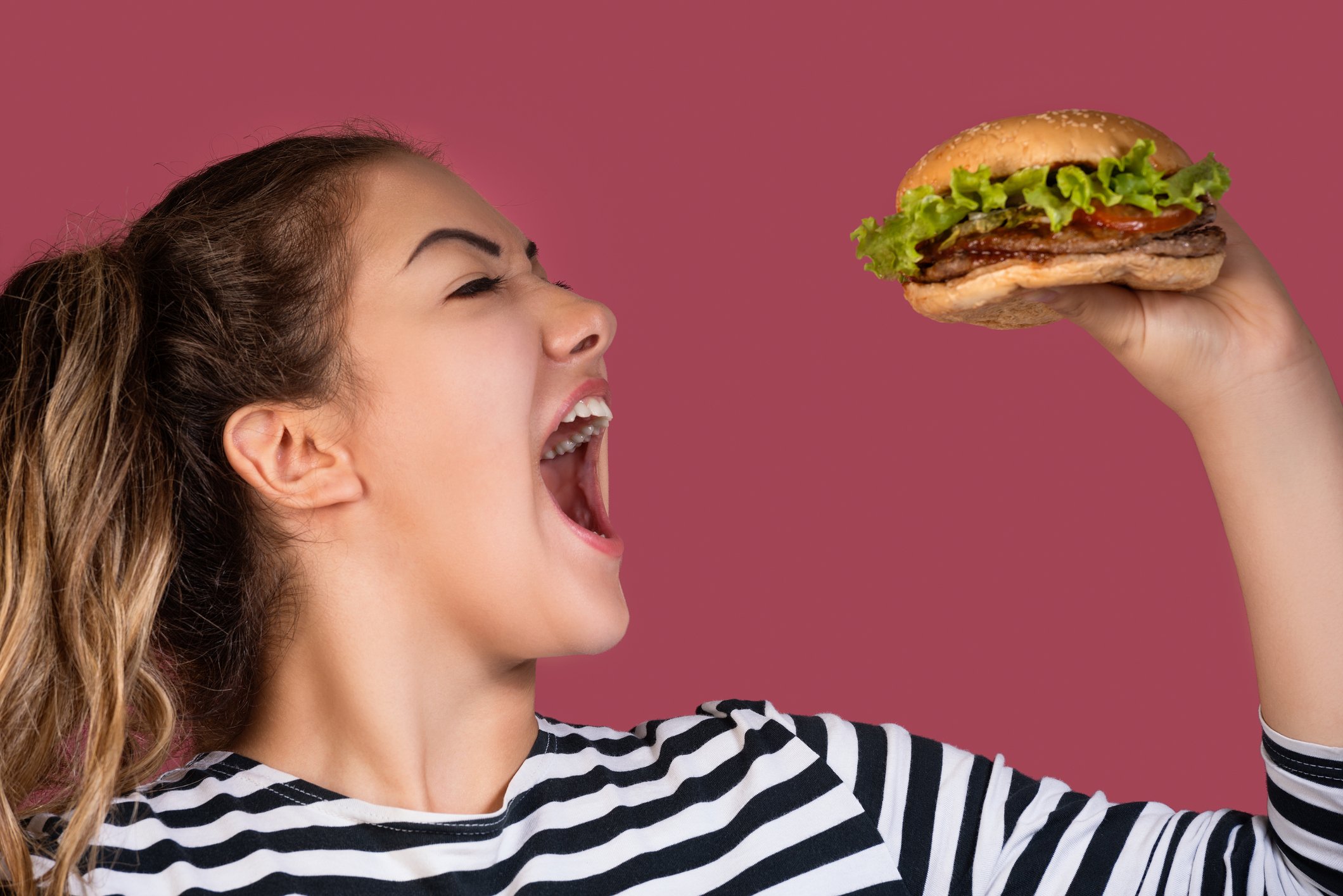 Woman taking a big bite of a burger