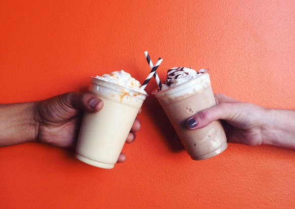 Photograph of two people 'toasting' with milkshakes