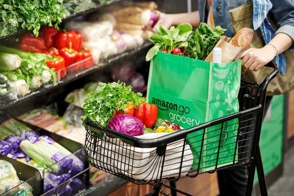 A grocery shopper pushes a cart and shops for produce in an Amazon Go store