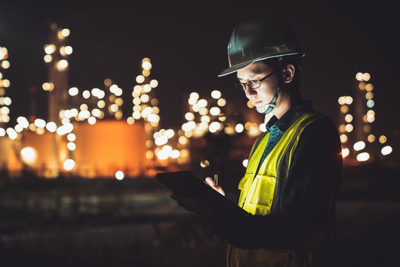 An engineer working at night at a refinery