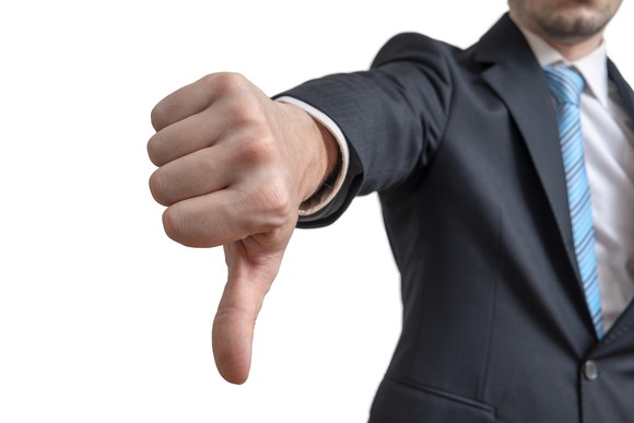 Man in business suit with a big thumb pointing down