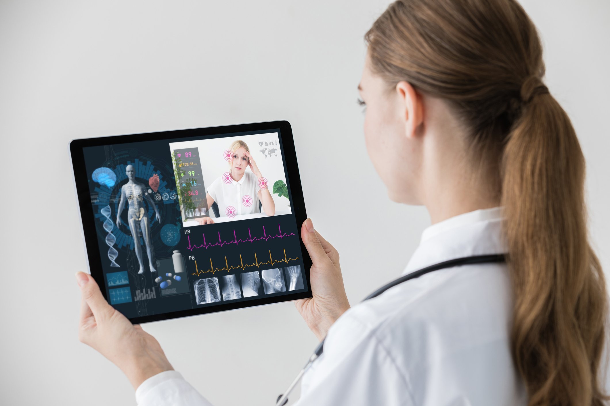Doctor holding tablet with patient face on screen.