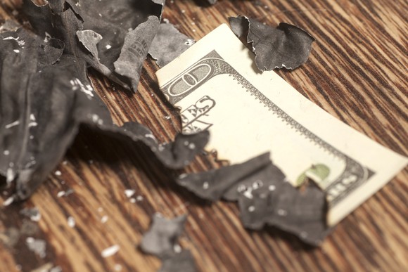 A burned piece of cash lies on a table.