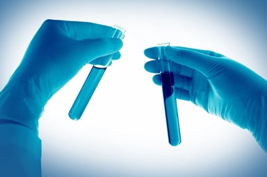 two gloved hands holding test tubes in each hand