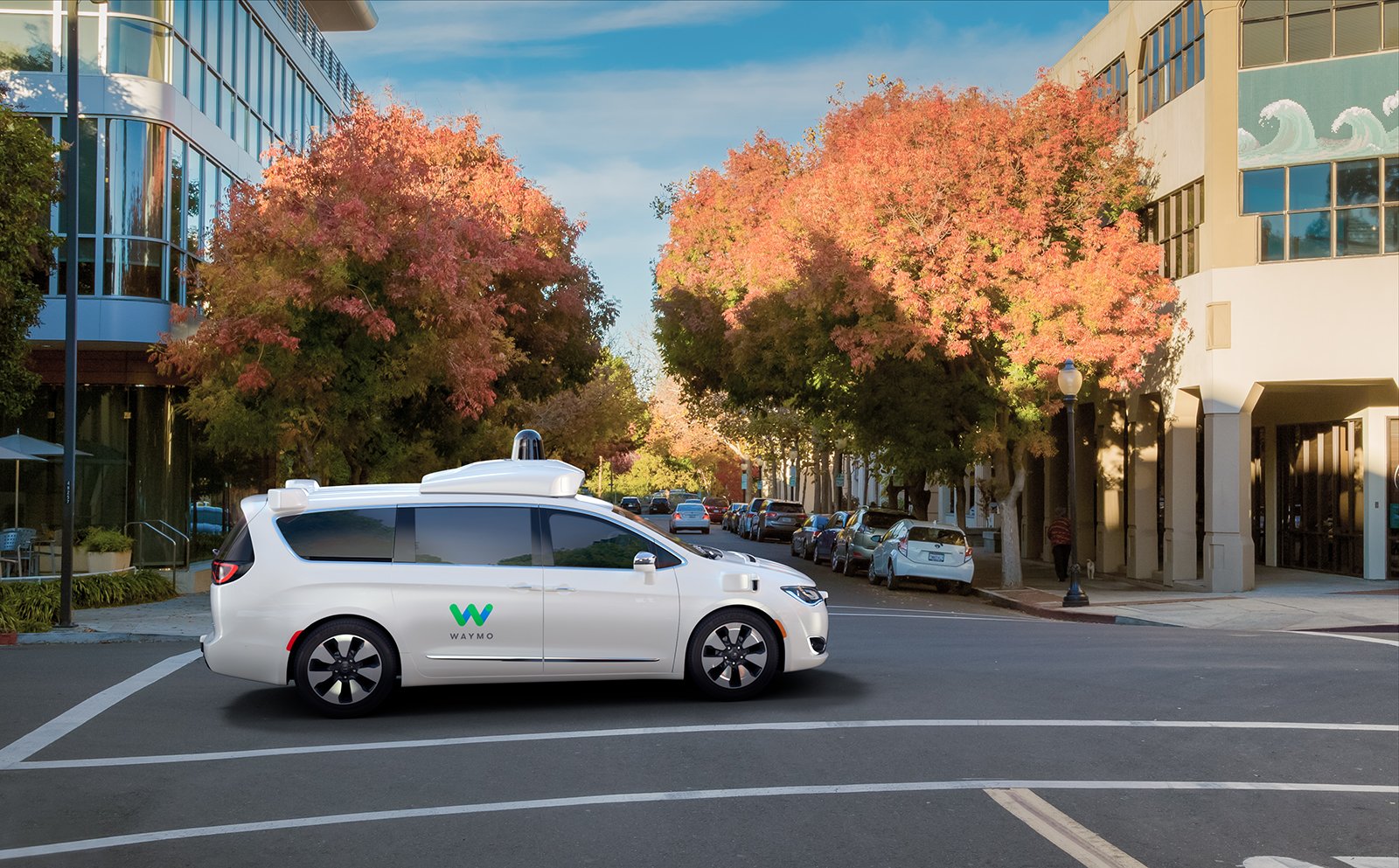 A Waymo-equipped Chrysler Pacifica minivan drives through an intersection.