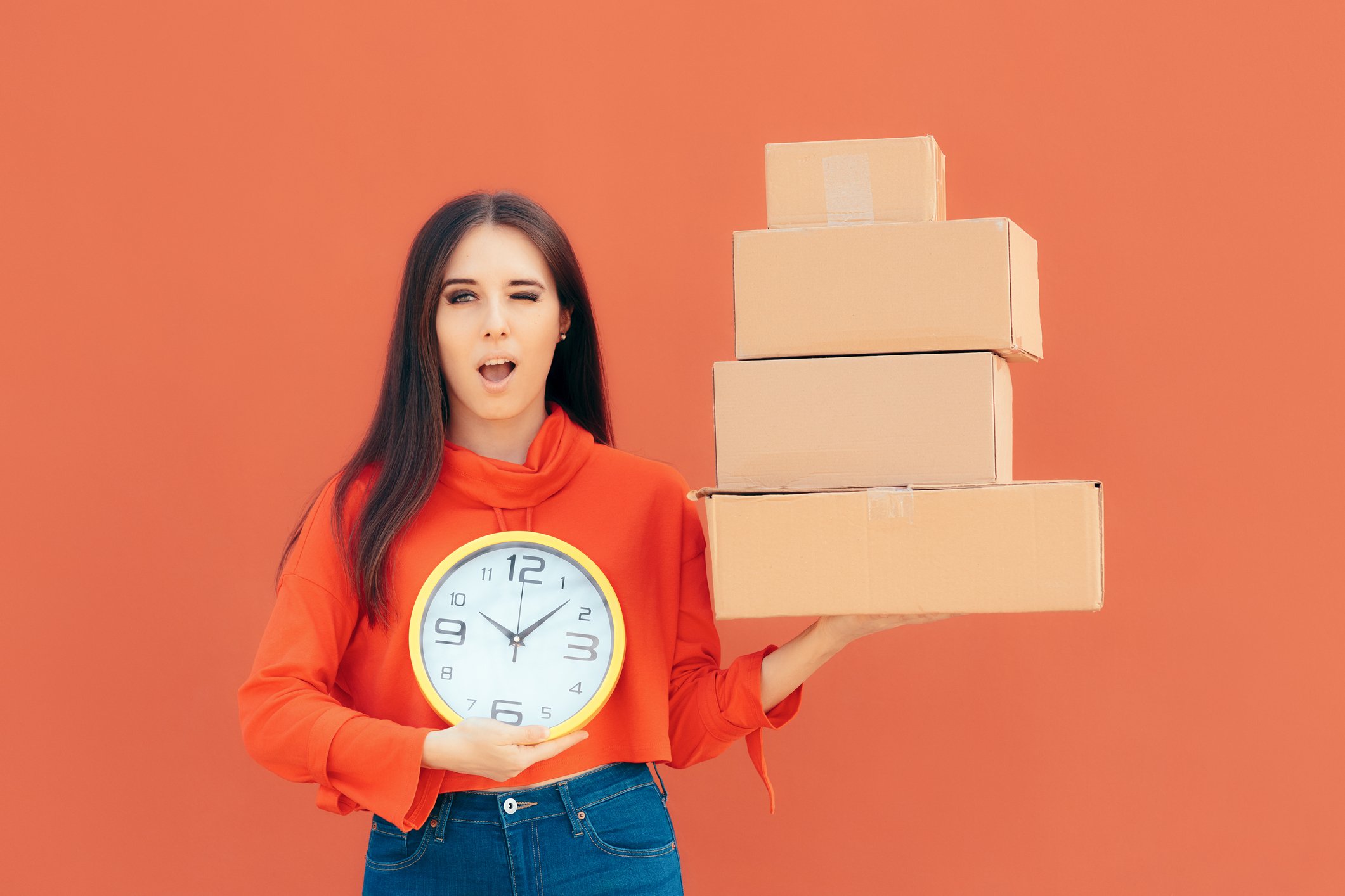 Woman holding delivery boxes and a clock to indicate timely delivery