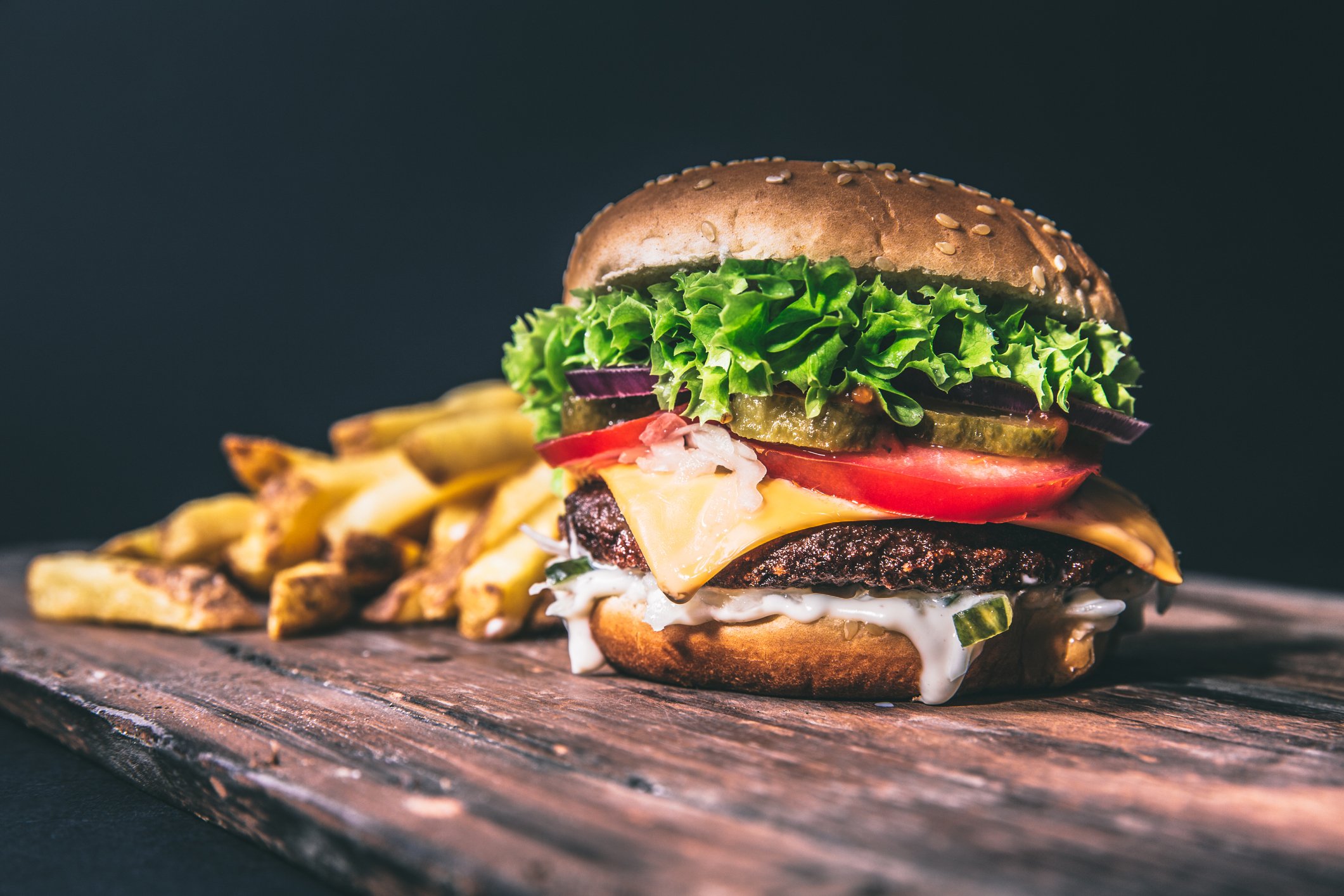 An artisan hamburger and fries on a wooden table.