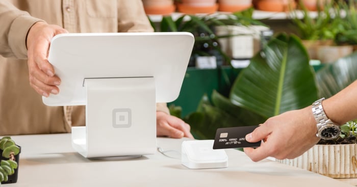 A shopper uses credit card to pay at a Square point-of-sale system