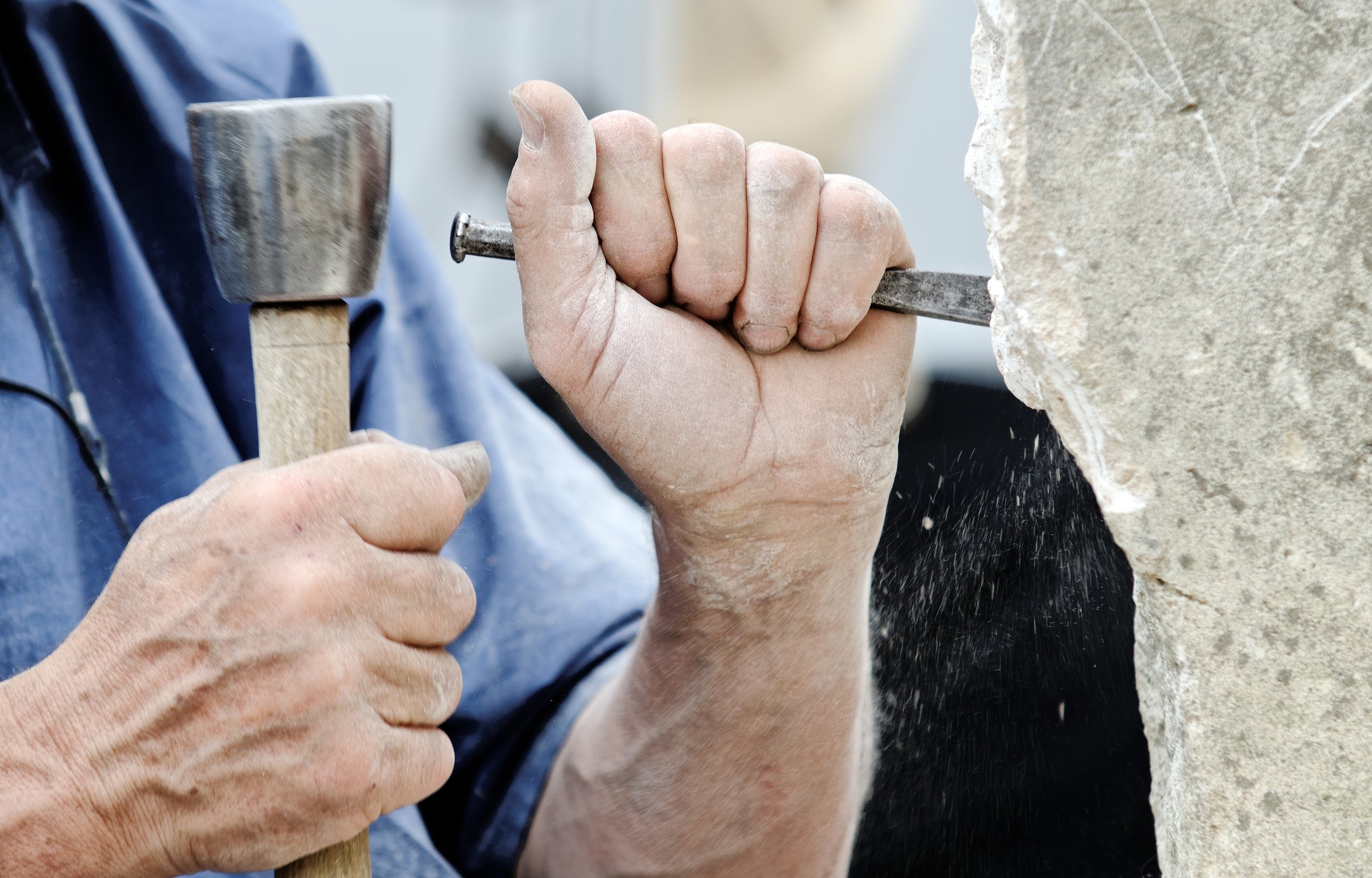 Man chiseling into a large stone.