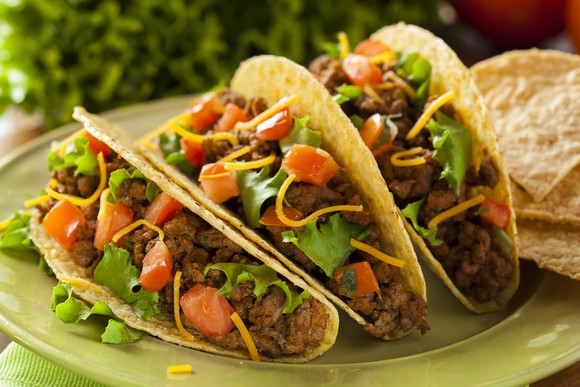Three tacos are on a plate. 
