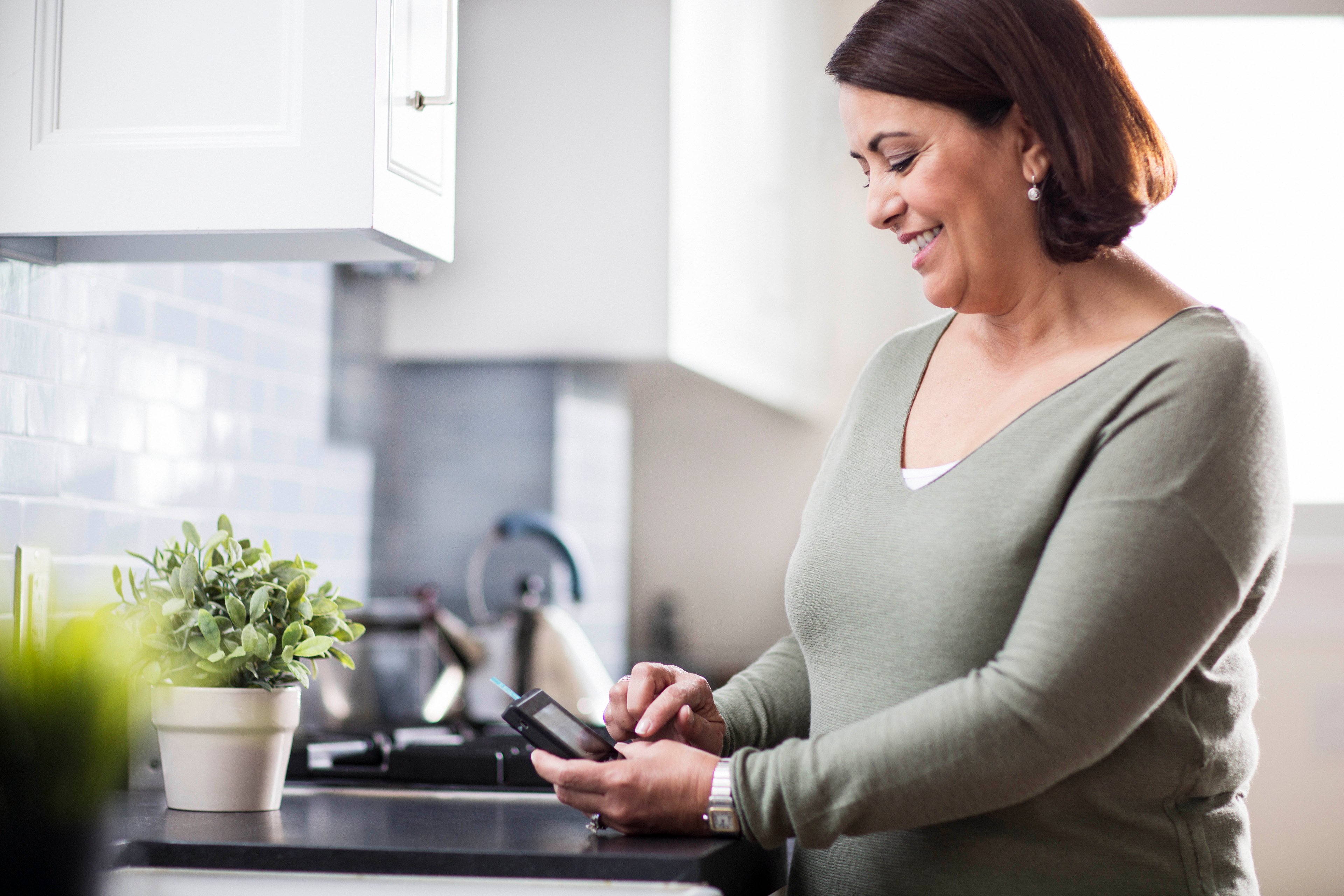 A woman using a device to check her blood glucose levels.