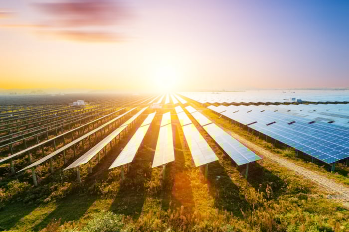 Solar panels with a bright sun in the background.