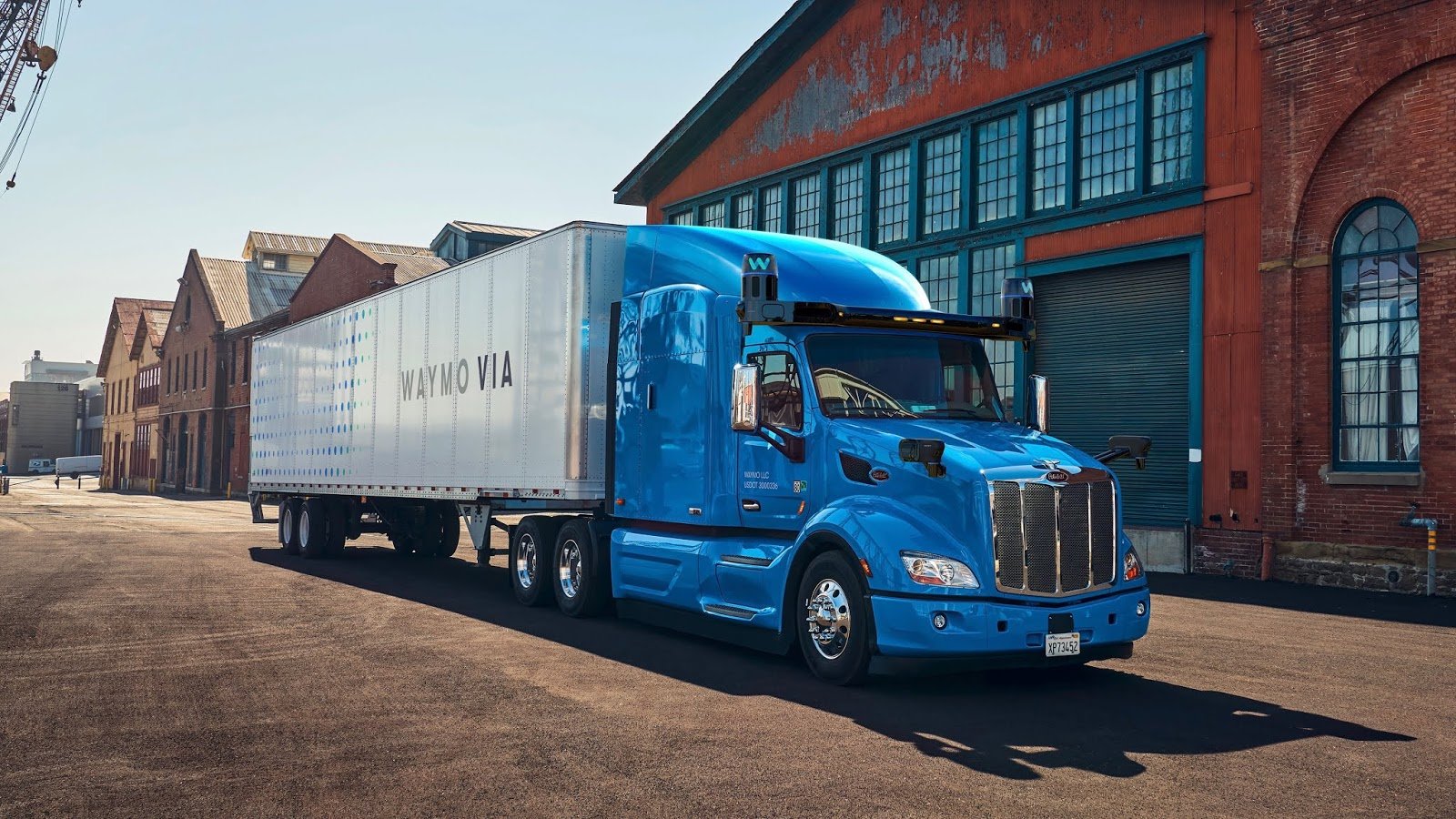 A tractor trailer truck parked in front of a warehouse.