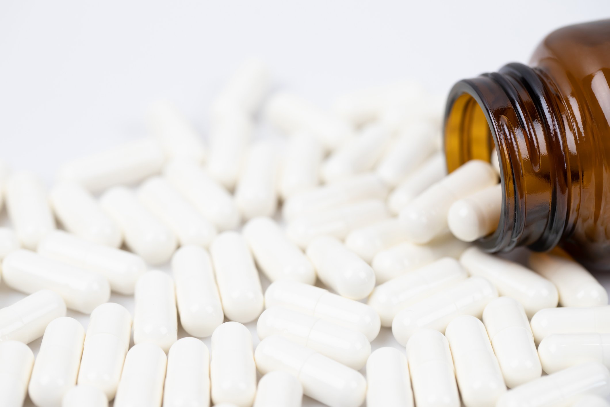White pills spill out of a bottle of prescription medication.