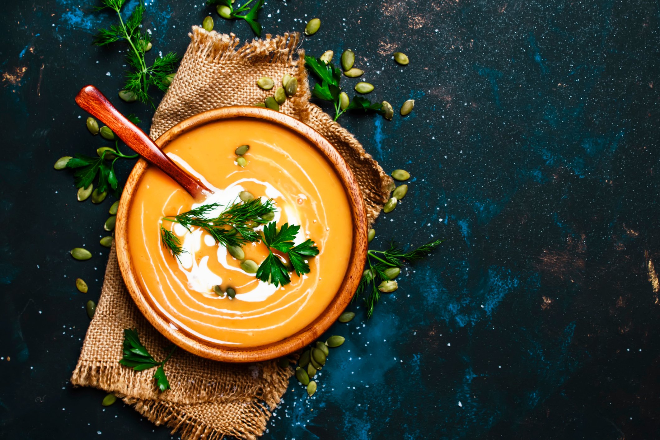 A bowl of creamy pumpkin soup, garnished with cilantro.