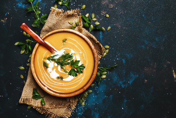 A bowl of creamy pumpkin soup, garnished with cilantro.