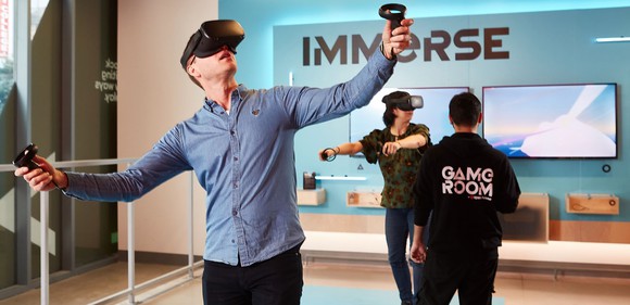 People wearing virtual reality headwear and playing a video game.