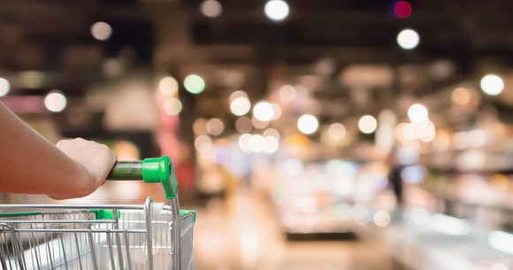 Close-up of a shopping cart being pushed through the grocery section of a warehouse-club store.