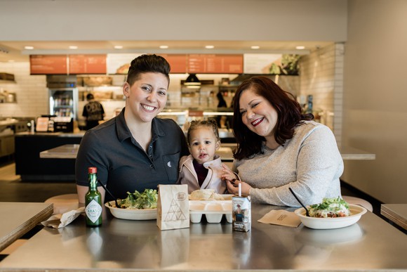 Two women sit with a toddler in a Chipotle.