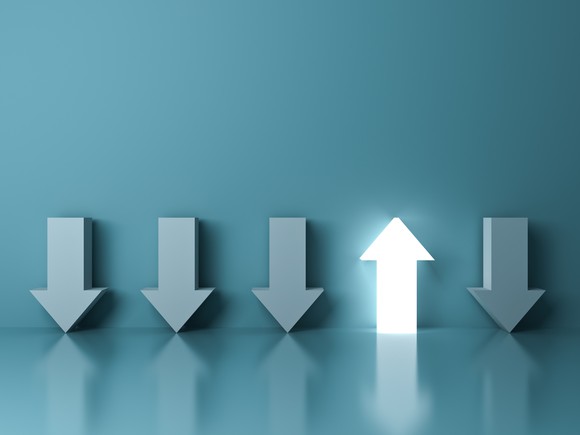 One lighted white arrow pointing up with four blue arrows pointing down