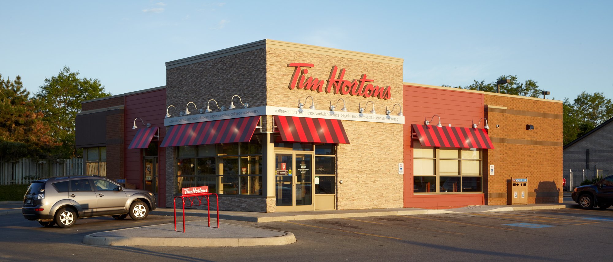 A Tim Horton's restaurant with an SUV parked outside.