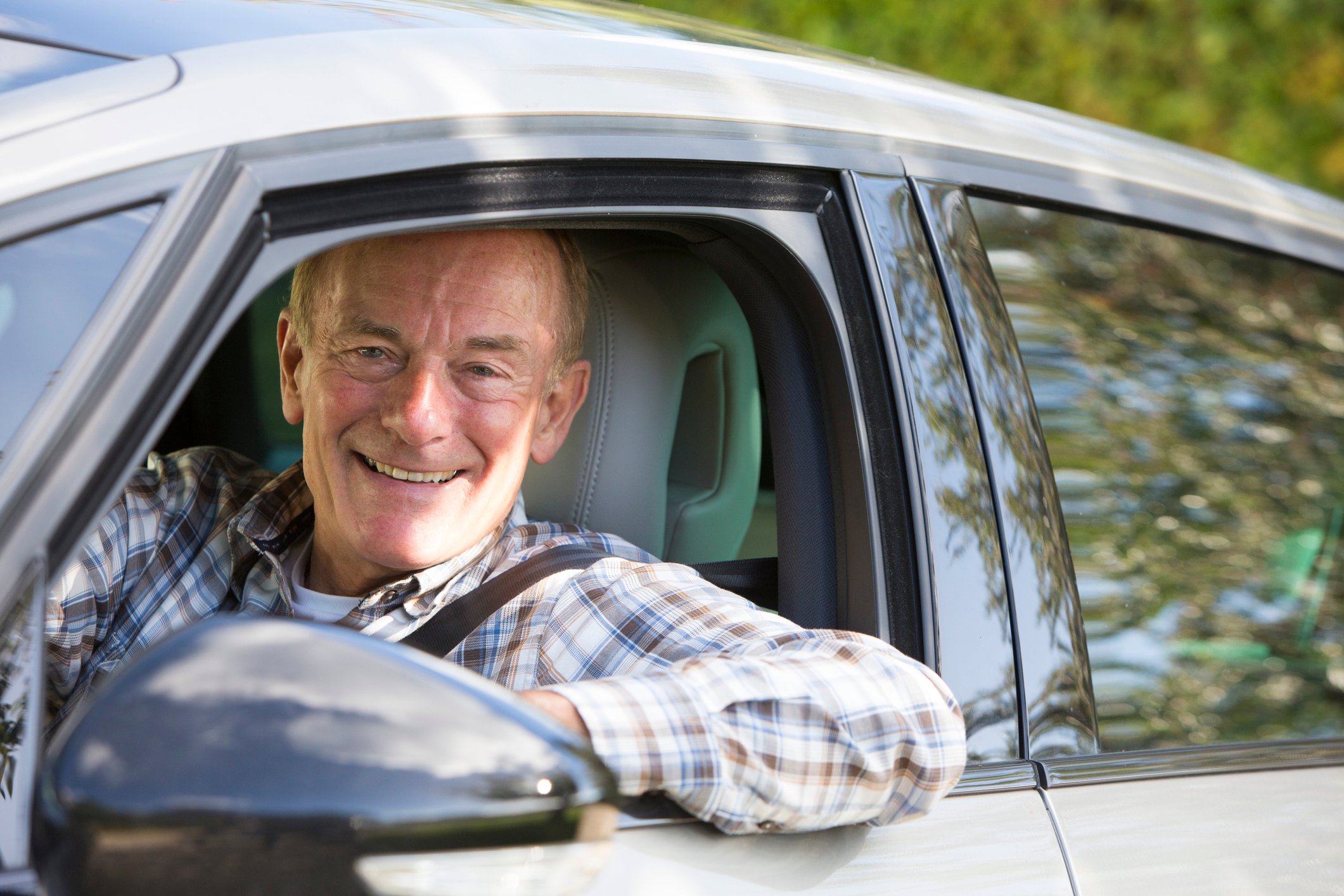 Smiling older man sitting in driver's seat of car