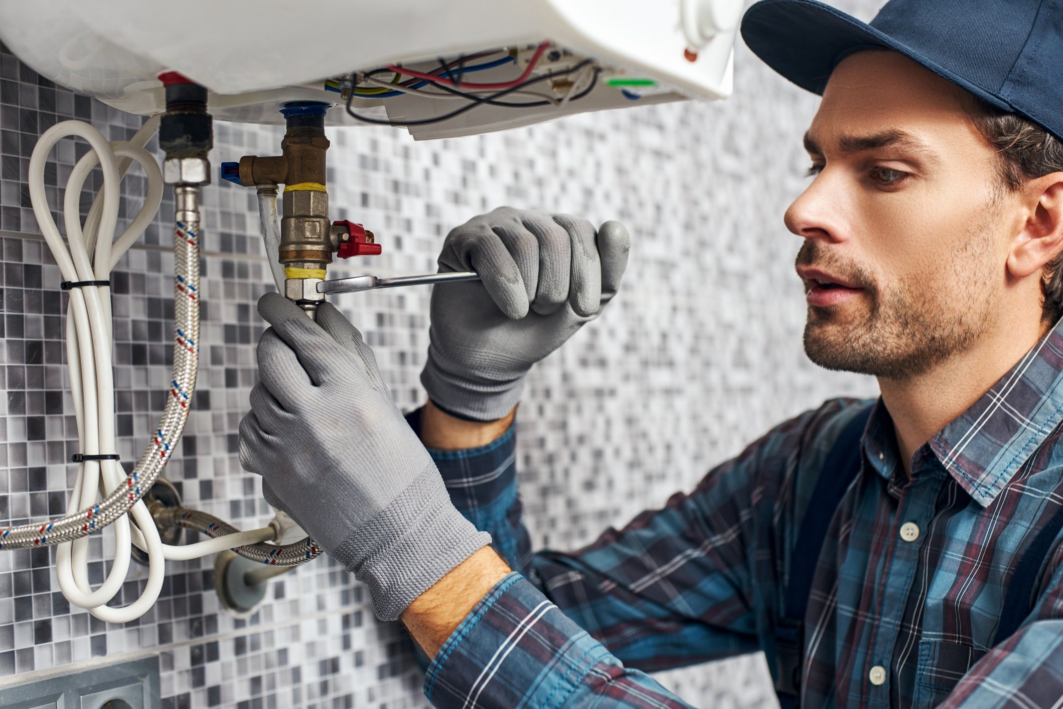 A plumber fixing a pipe underneath a sink.