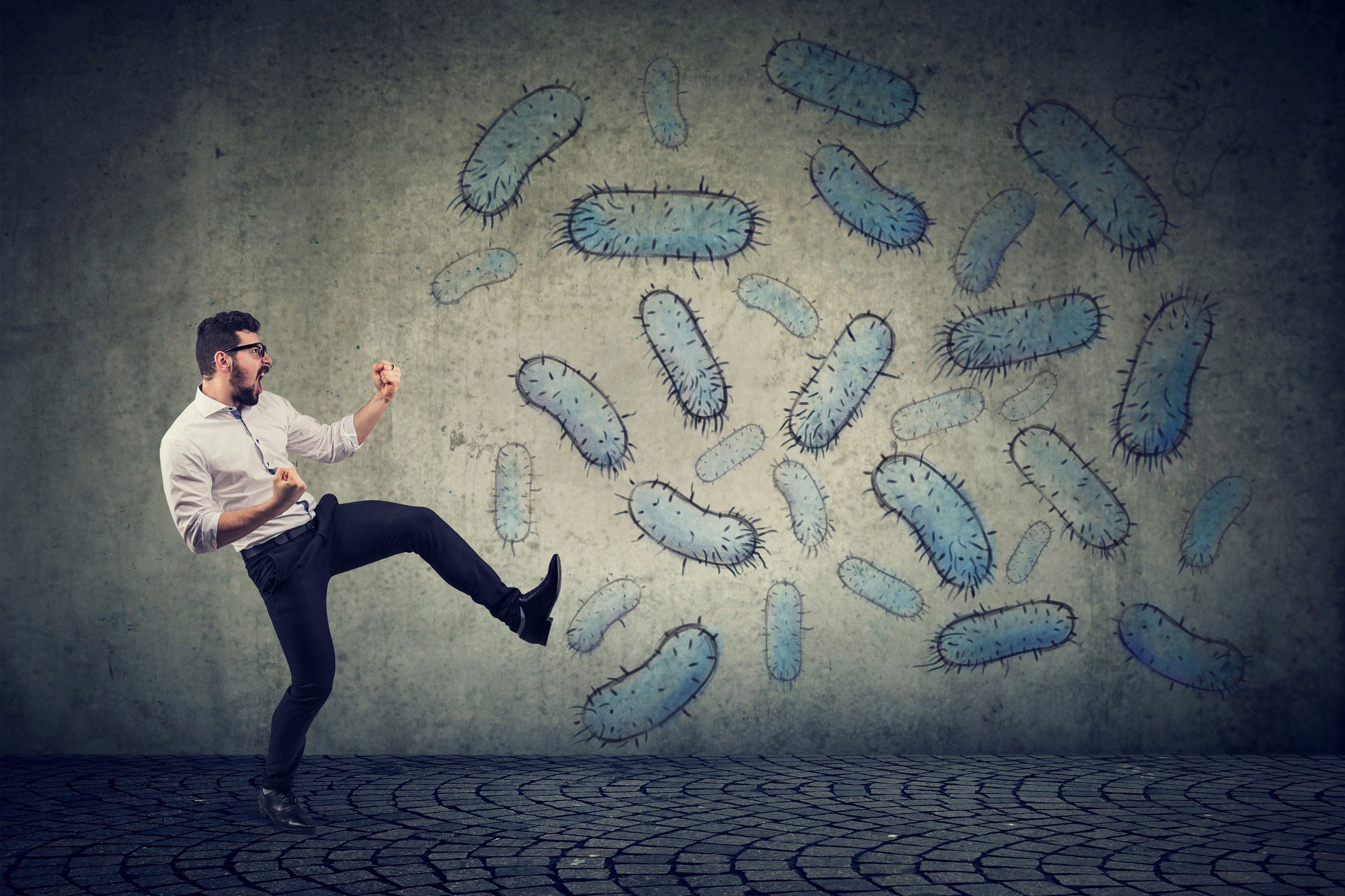Virus particles painted on a wall. A man is standing in front of the wall in a fighting pose.
