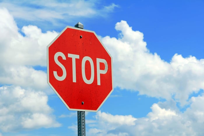 Red stop sign against a blue sky with clouds.