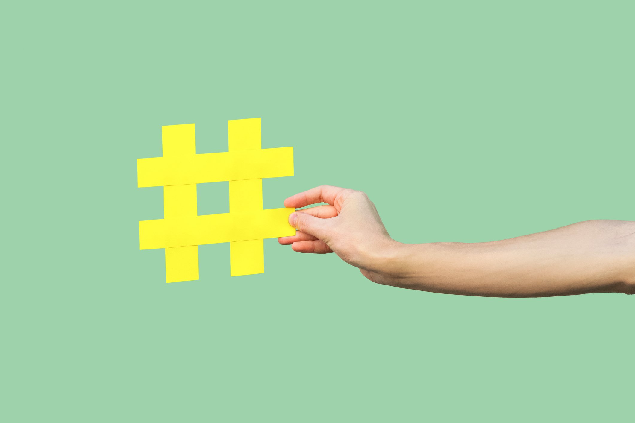 A hand holds a yellow hashtag symbol