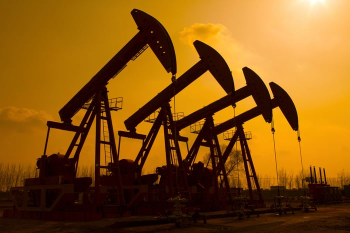 Four oil pumps silhouetted against a sunny sky.