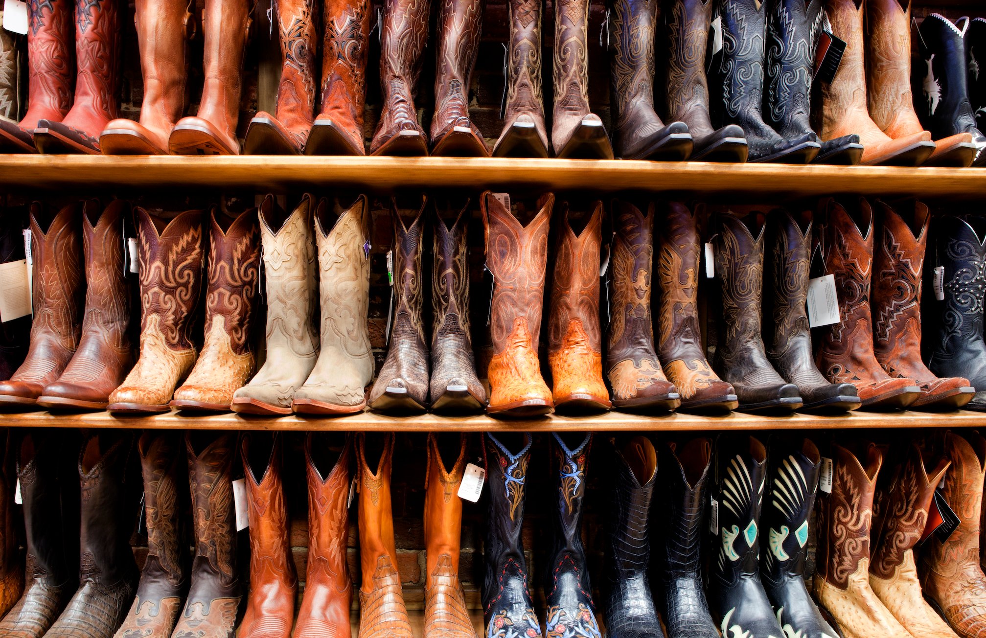 Rows of cowboy boots on a store's shelves. 