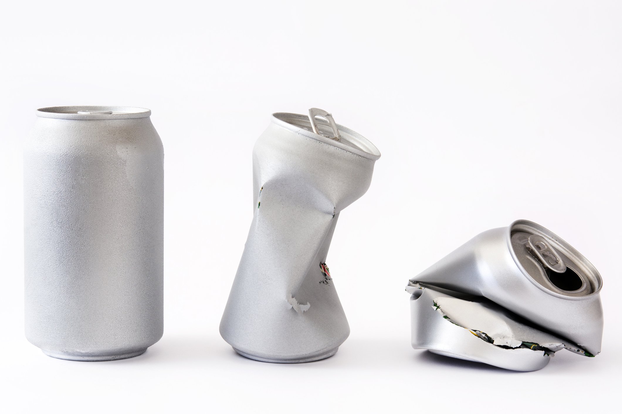 An aluminum can, a partially crushed aluminum can, and a fully crushed aluminum can. 