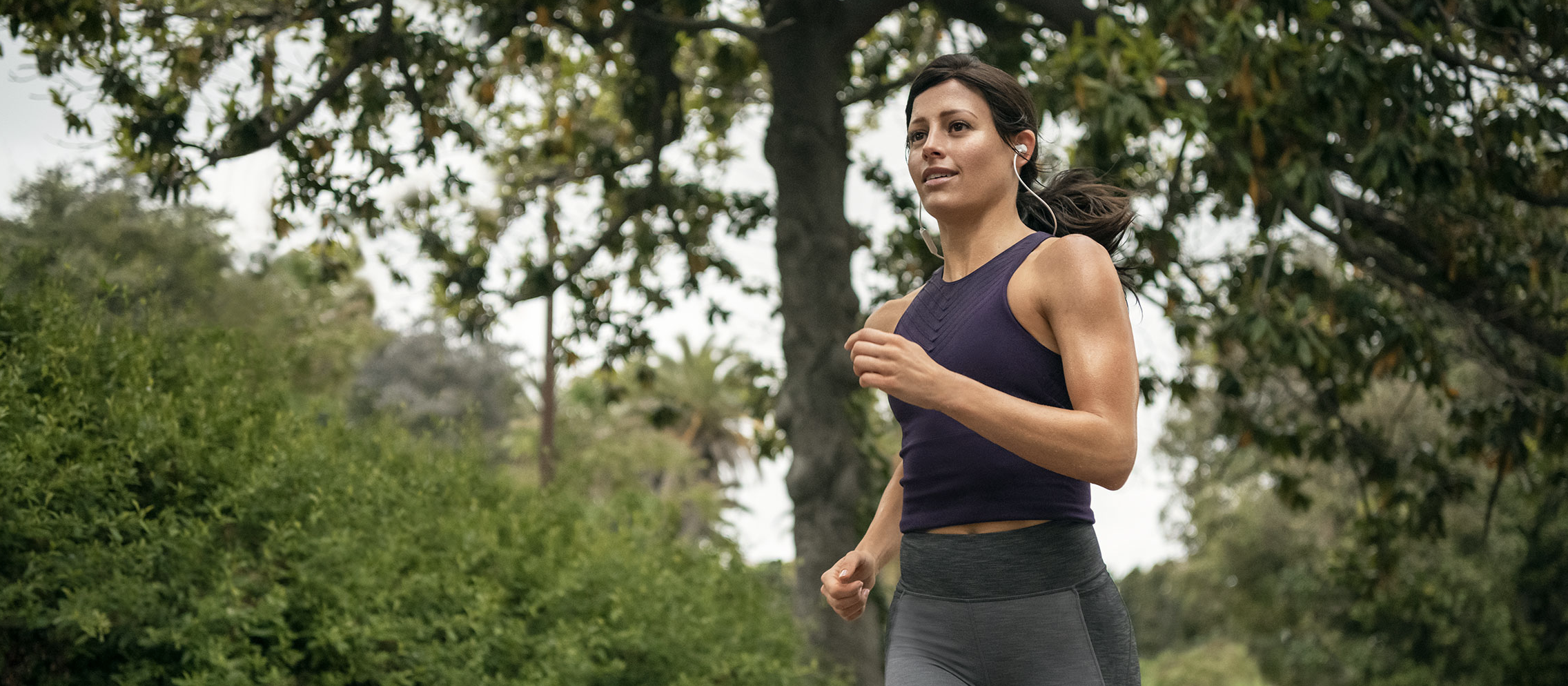A woman wearing earbuds while running.