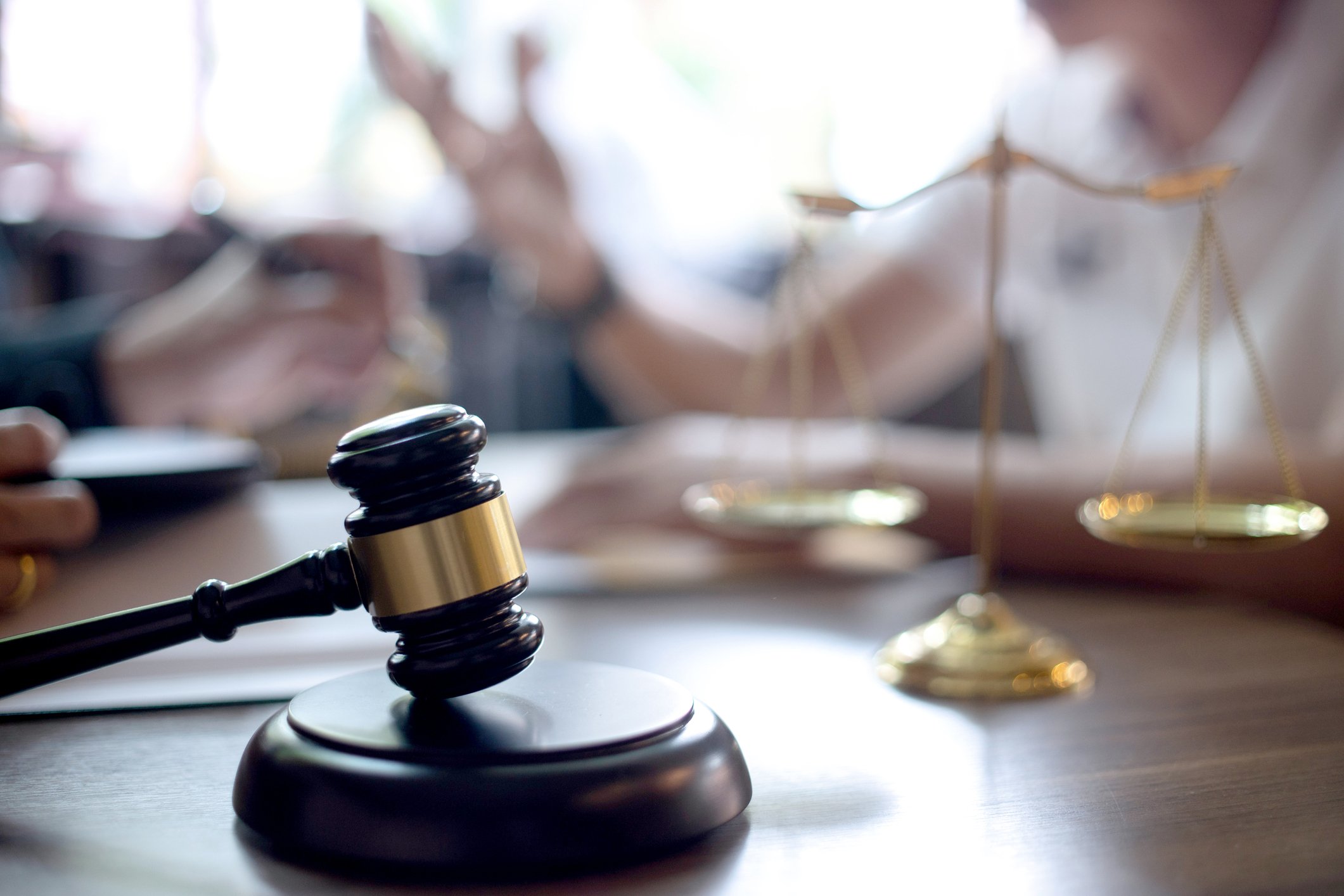 A gavel and scales of justice sit on a desk.
