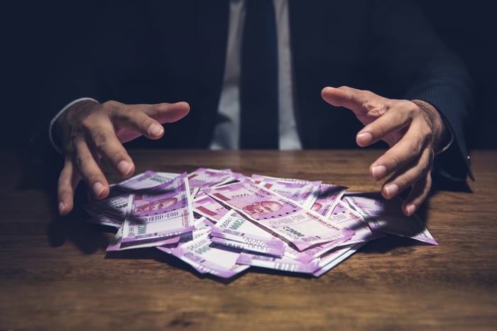 Hands reach out to grab a big pile of money