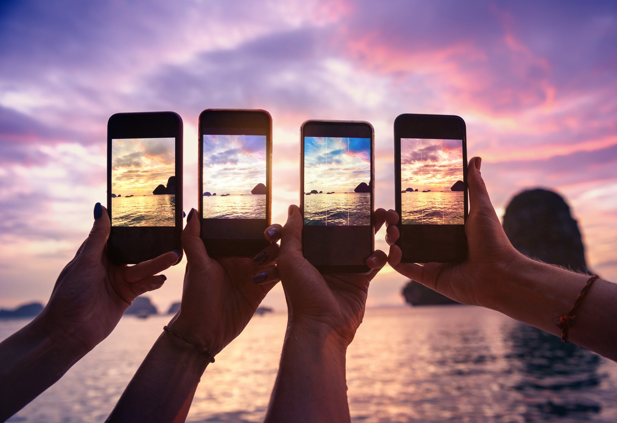 Four smartphones being use to take pictures of a coast.