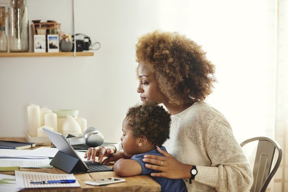 Woman working from home with child on lap.