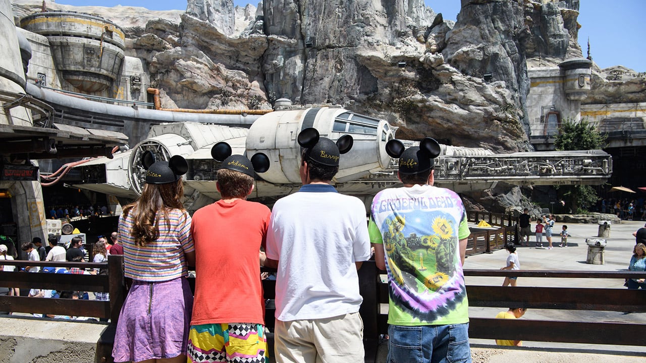 Three boys and a girl wearing Mickey Mouse ears while looking at the Star Wars attraction at one of Disney's theme parks