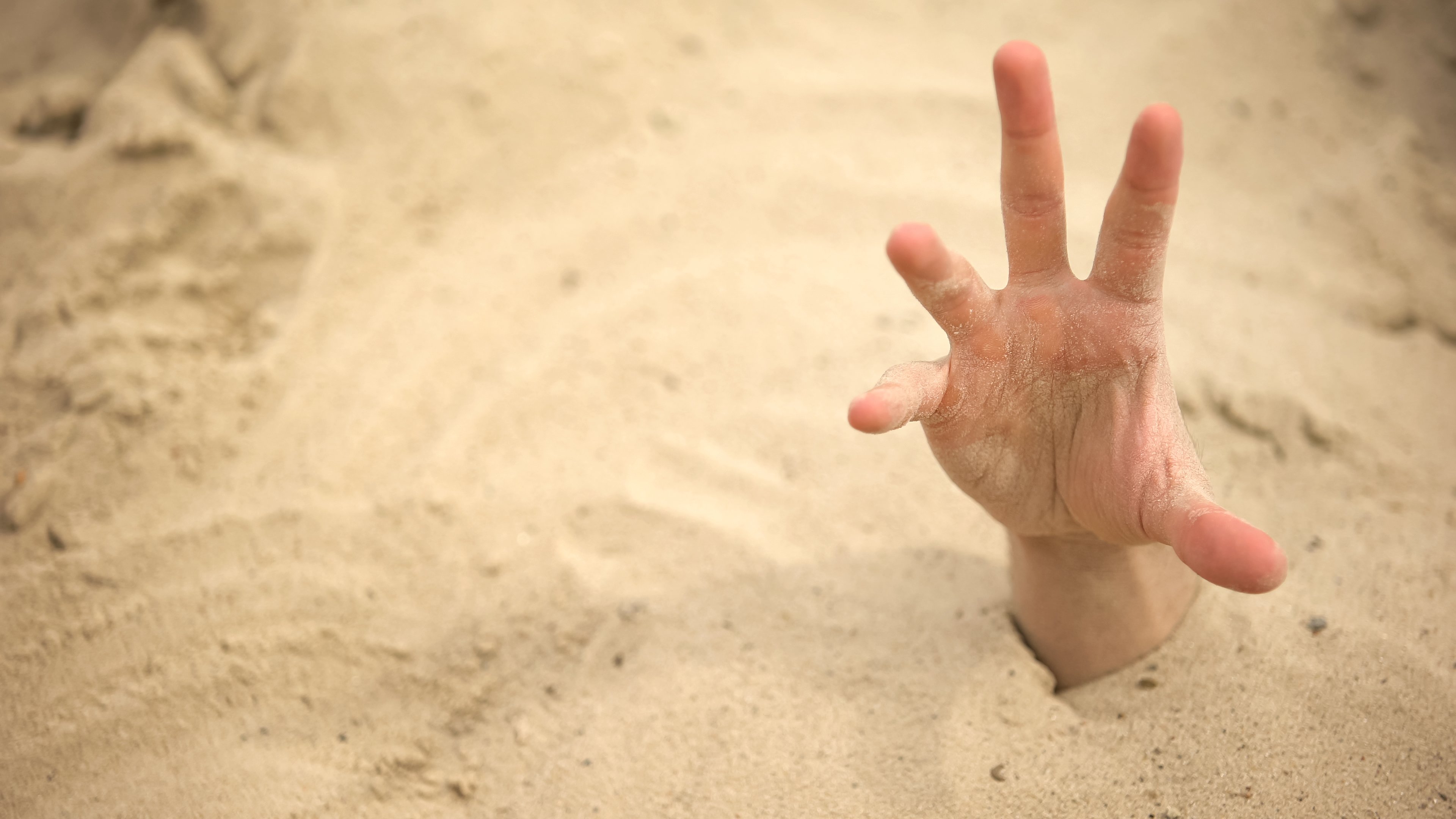 Hand sticking out of sand