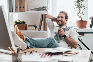 man with feet on desk smiling relaxing thinking