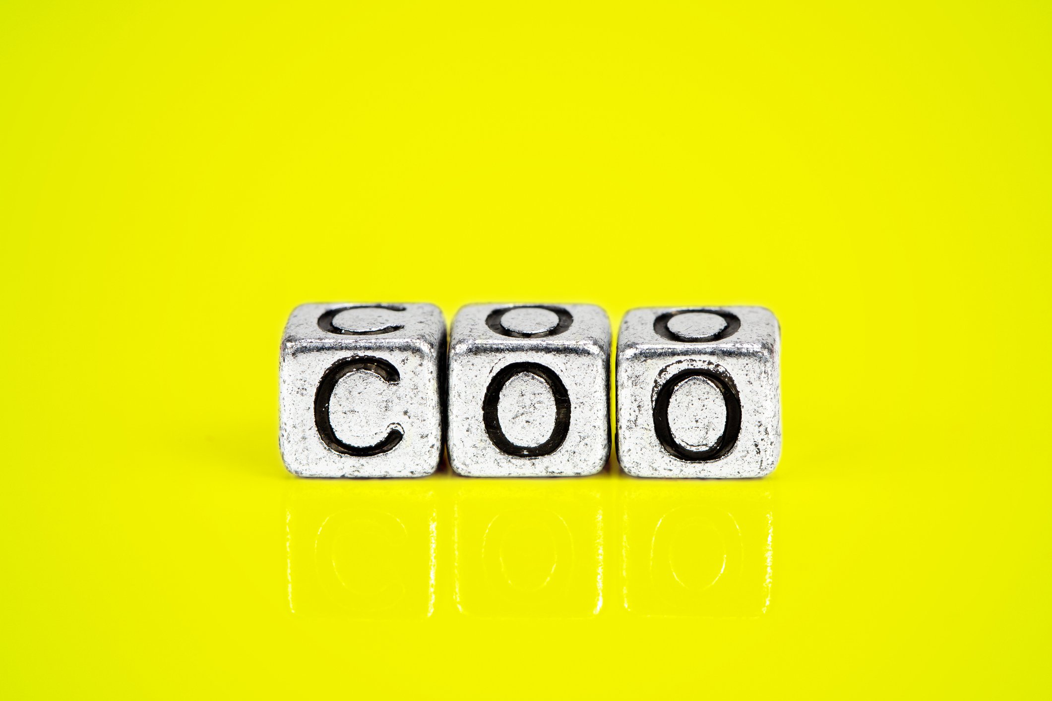 Three blocks that spell out COO on a yellow background