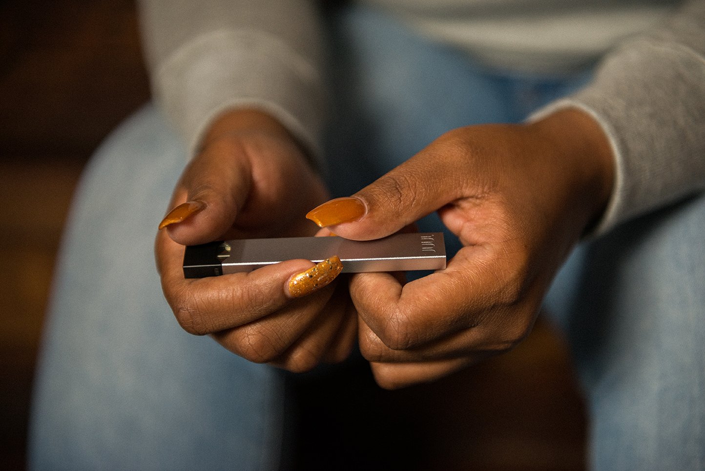 Close-up of a person's hands clutching a Juul device.