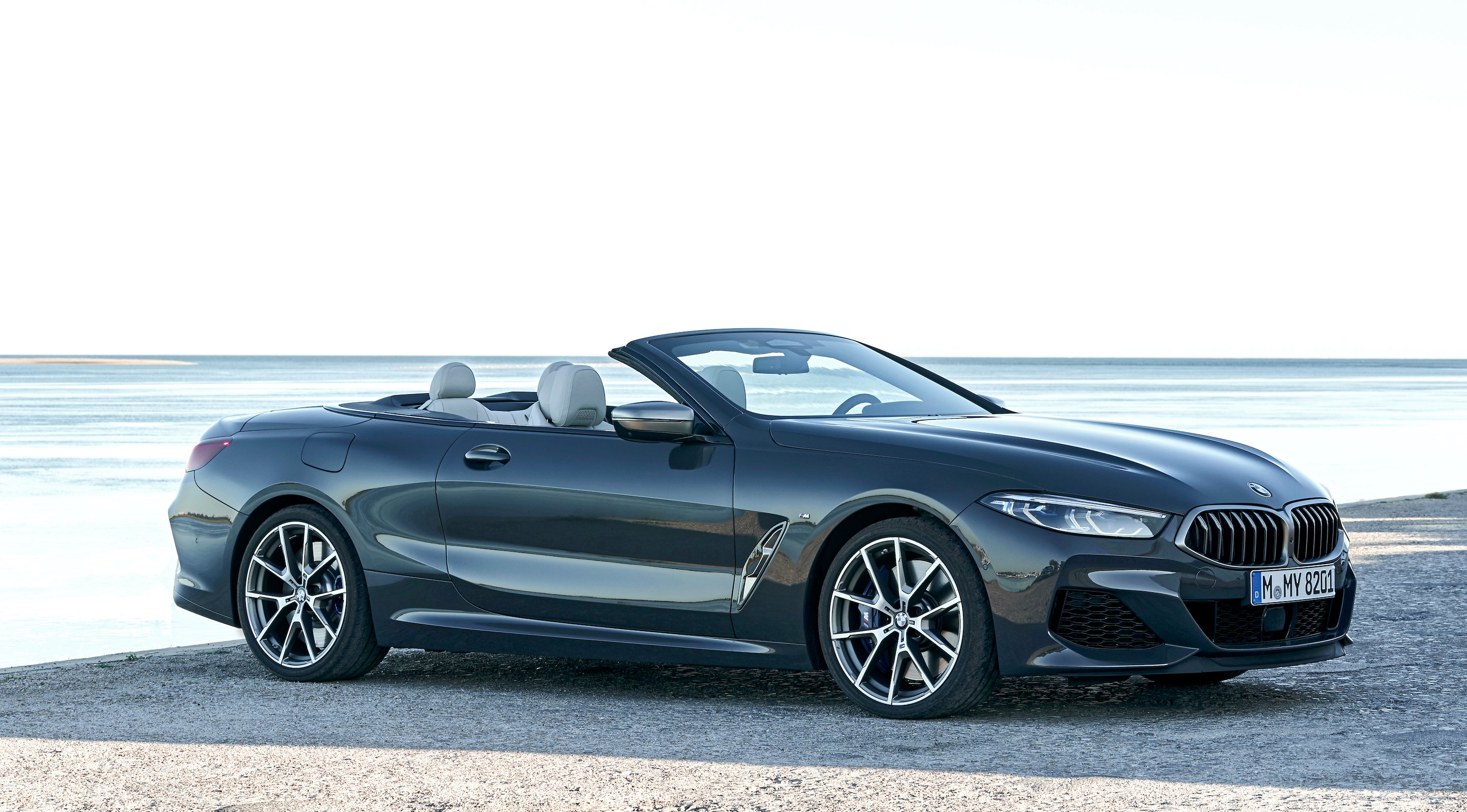 A BMW 8 Series convertible, a 2-door luxury car, parked on a beach