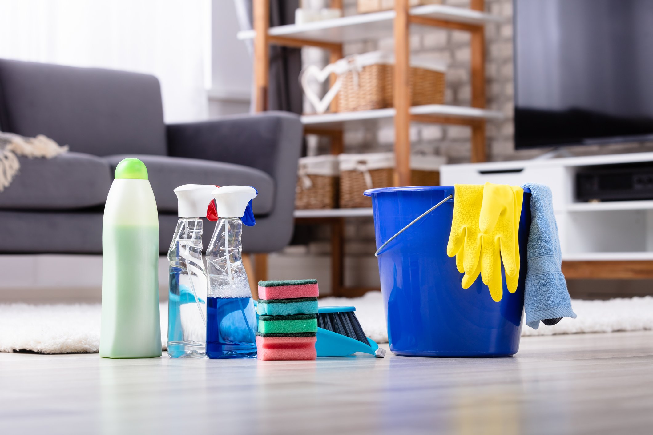 Cleaning supplies, a bucket, and rubber gloves on the floor of a living room