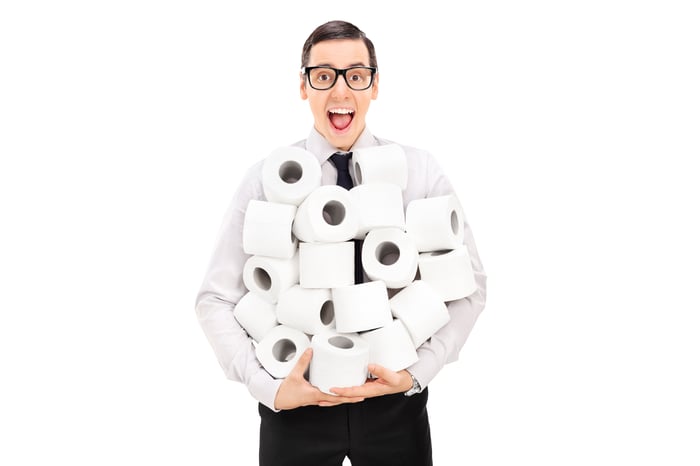 Smiling man holding lots of rolls of toilet paper